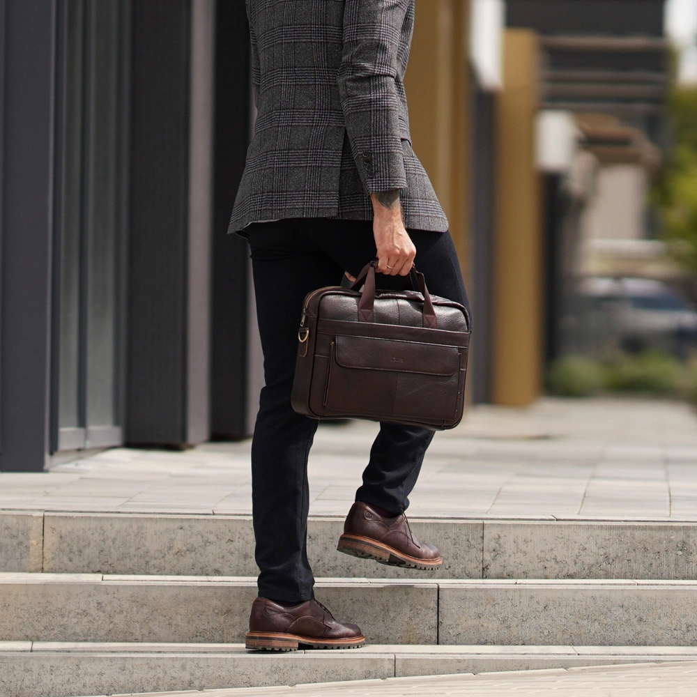 Ciemnobrązowa torba męska do pracy Solier SL46 trzymana w dłoni przez mężczyznę wchodzącego po schodach