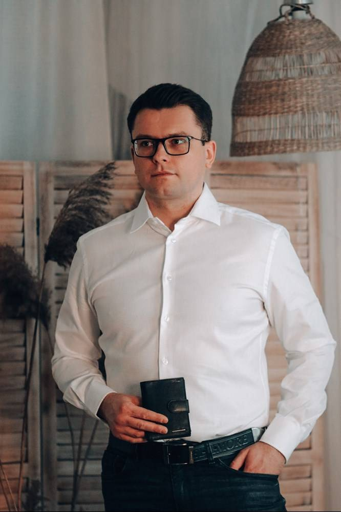 Granatowy pasek męski Beltimore 520 95 cm, noszony przez mężczyznę w białej koszuli, w dłoni portfel