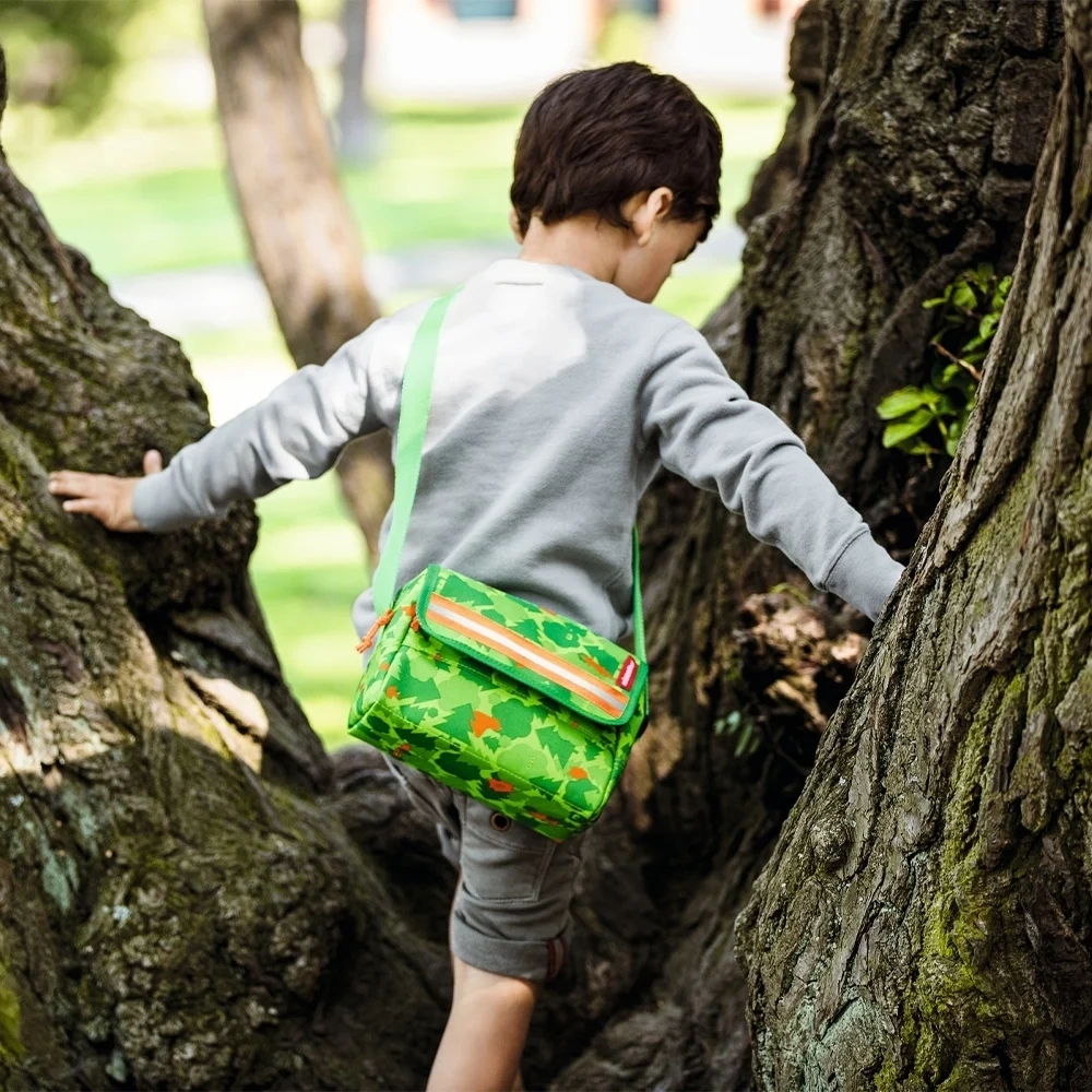 Zielona torba Reisenthel everydaybag kids noszona na ramieniu przez dziecko wspinające się na drzewo