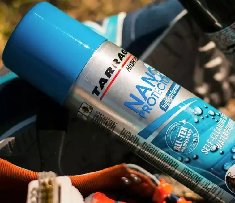 Zestaw w sprayu do skóry i tekstyliów Tarrago - puszka Nano Protector z bliska na tle sprzętu outdoorowego