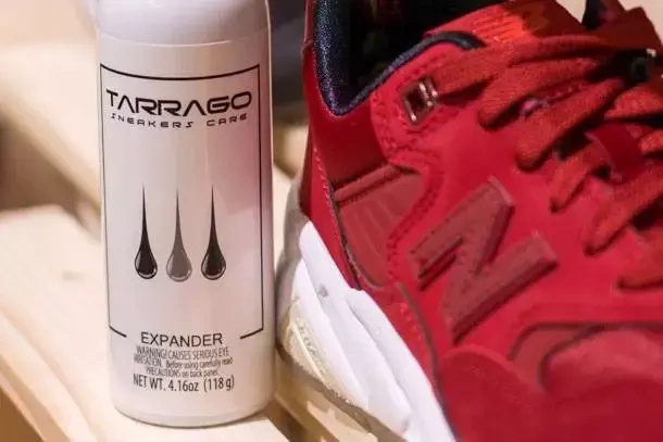 Rozciągacz w sprayu do butów Tarrago - puszka obok czerwonego sneakersa