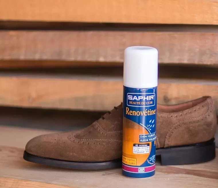 Renowator w sprayu do zamszu i nubuku Saphir niebieski - puszka Renovétine obok zamszowego buta