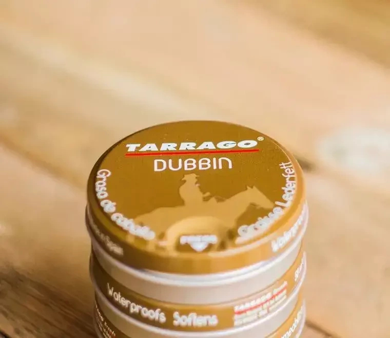 Tłuszcz do skór gładkich Tarrago bezbarwny - puszki Dubbin w stosie na drewnie
